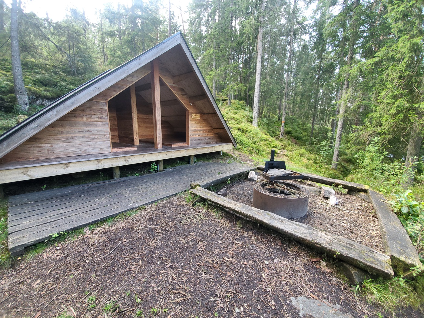 Et shelter og en bålplads omgivet af skov.